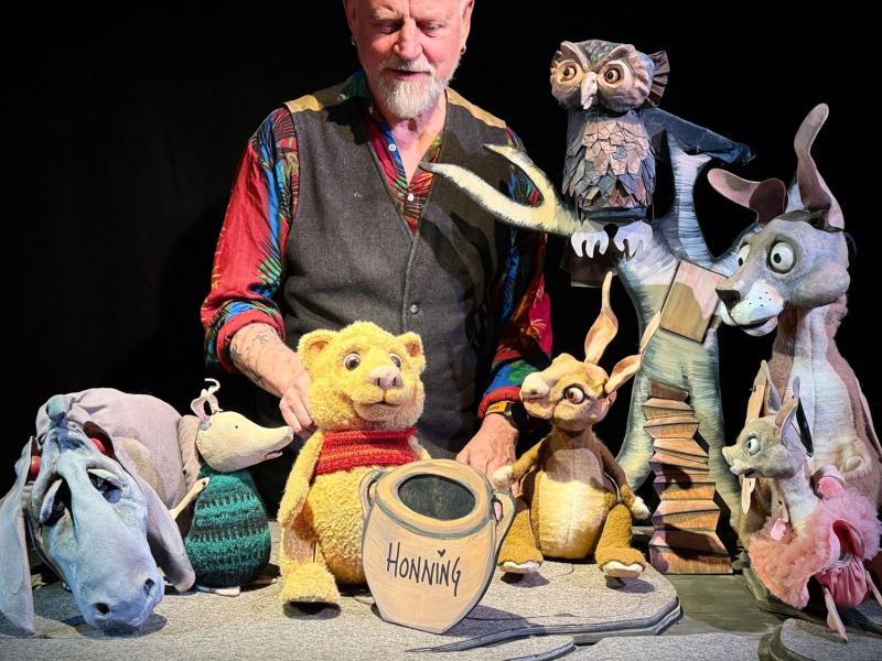 Billedet viser en mand og karaktererne fra Peter Plys bøgerne